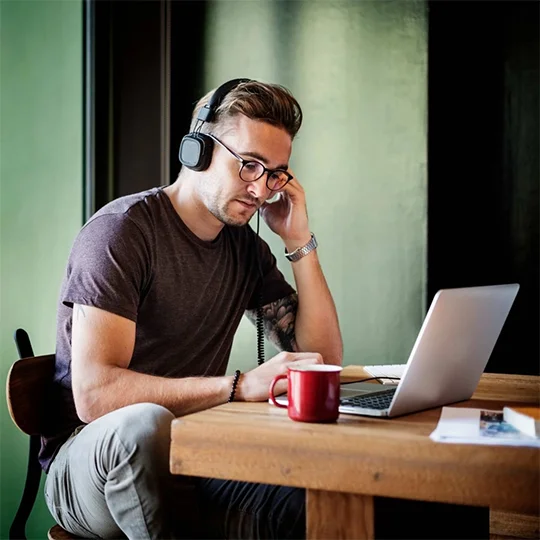 Listener wearing headphones working on a laptop