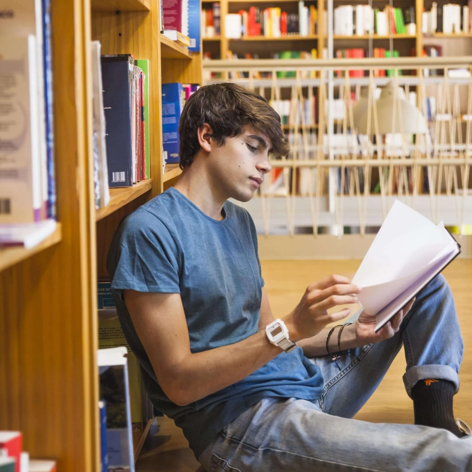 Young reader sitting among bookstore shelves, turning the pages of a book